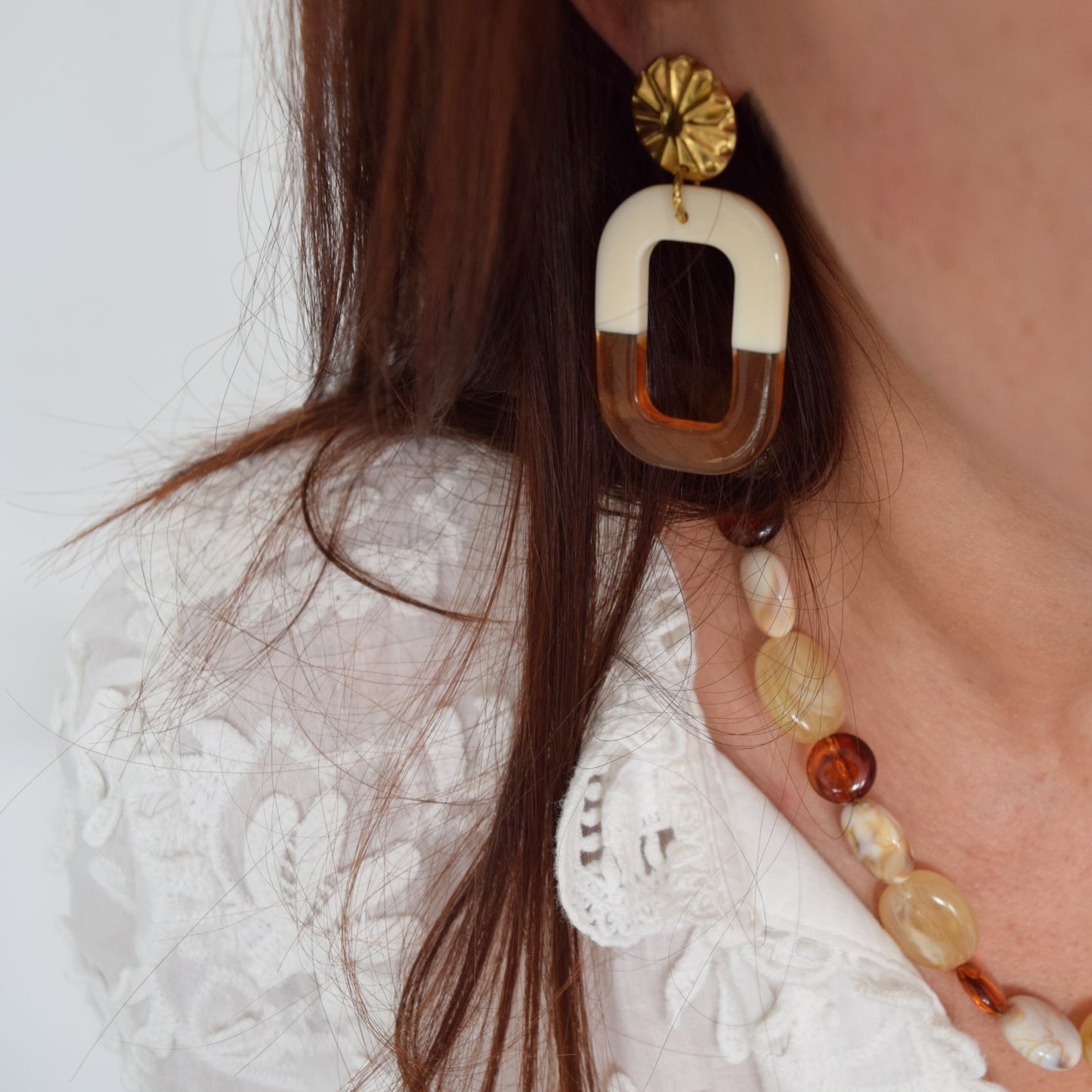 Gros plan sur boucles d’oreilles Sienna dorées, pendentif rectangulaire bicolore crème et ambre