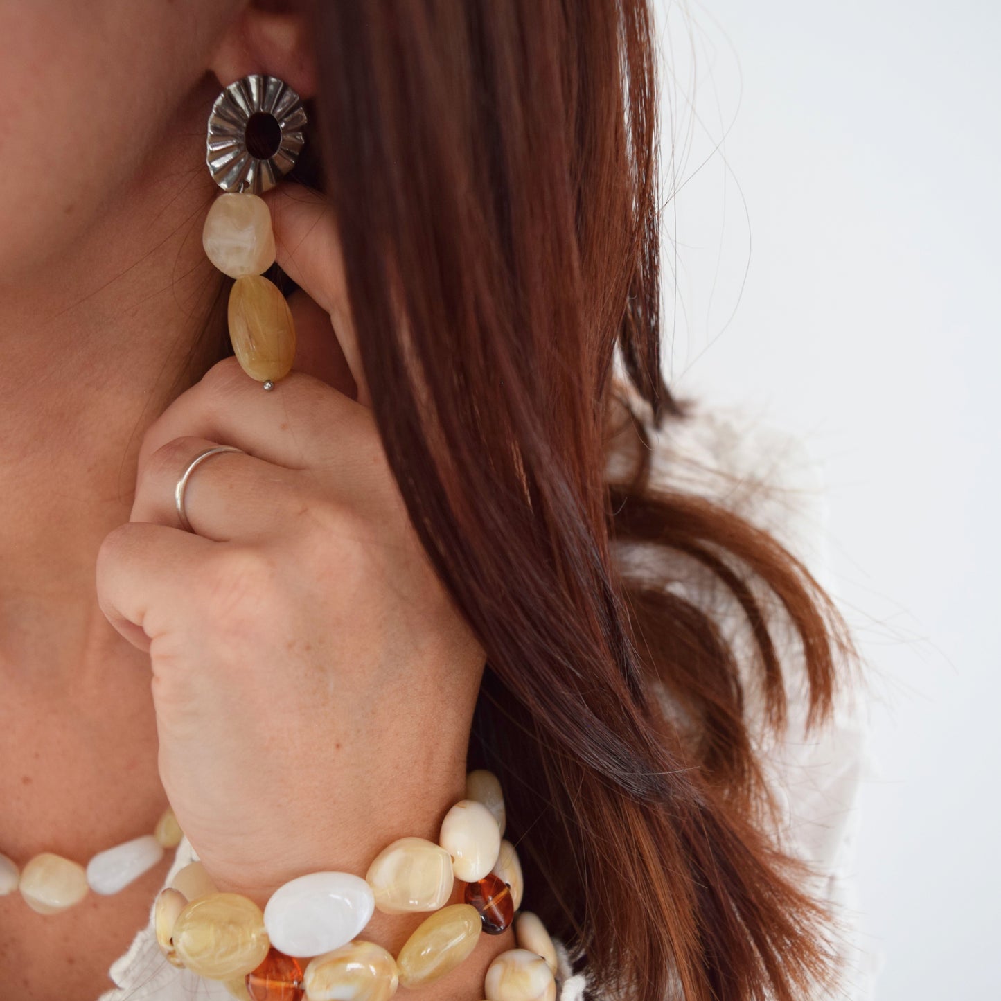 Boucles d’oreilles ÉLISE portées sur oreille, deux perles beige suspendues à une puce dorée texturée