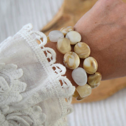 Bracelet fait main en perles blanches et beige porté au poignet.