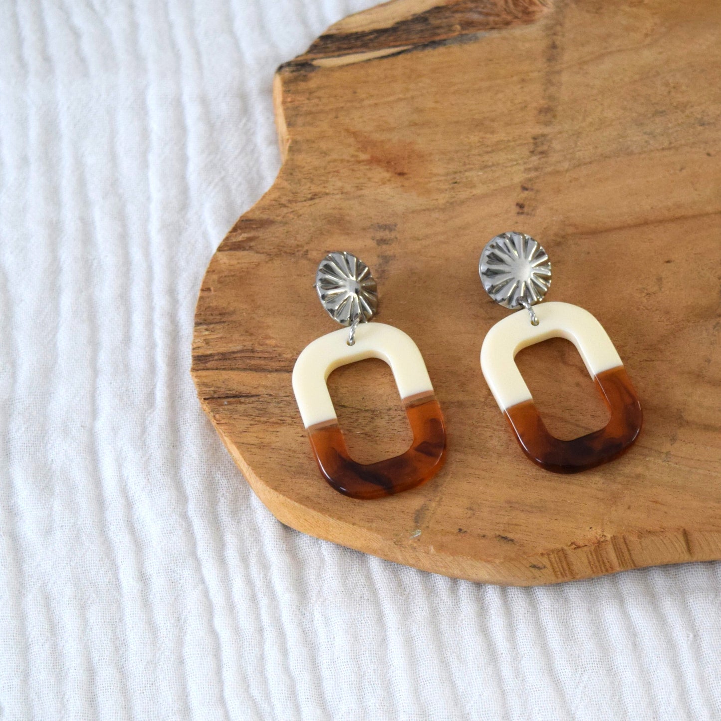 Détail du pendentif en résine ambrée et crème, finition brillante et forme géométrique ovale.