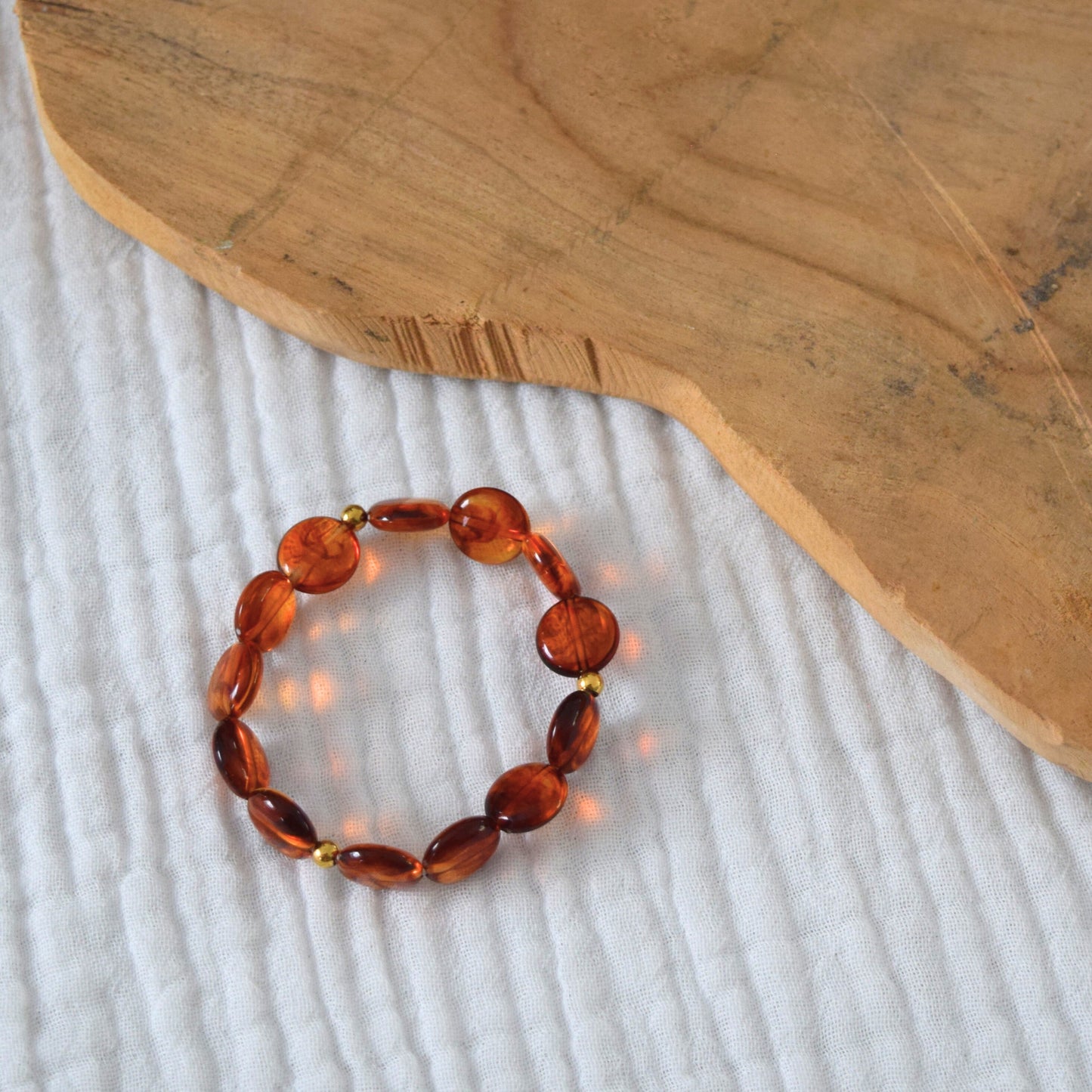 Bracelet élastique fait main, perles acryliques ambre sur fond clair.