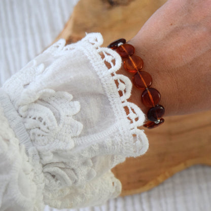 Bracelet couleur ambre sur poignet femme, bijou élastique avec perles rondes et éclats chauds, fabrication artisanale française.