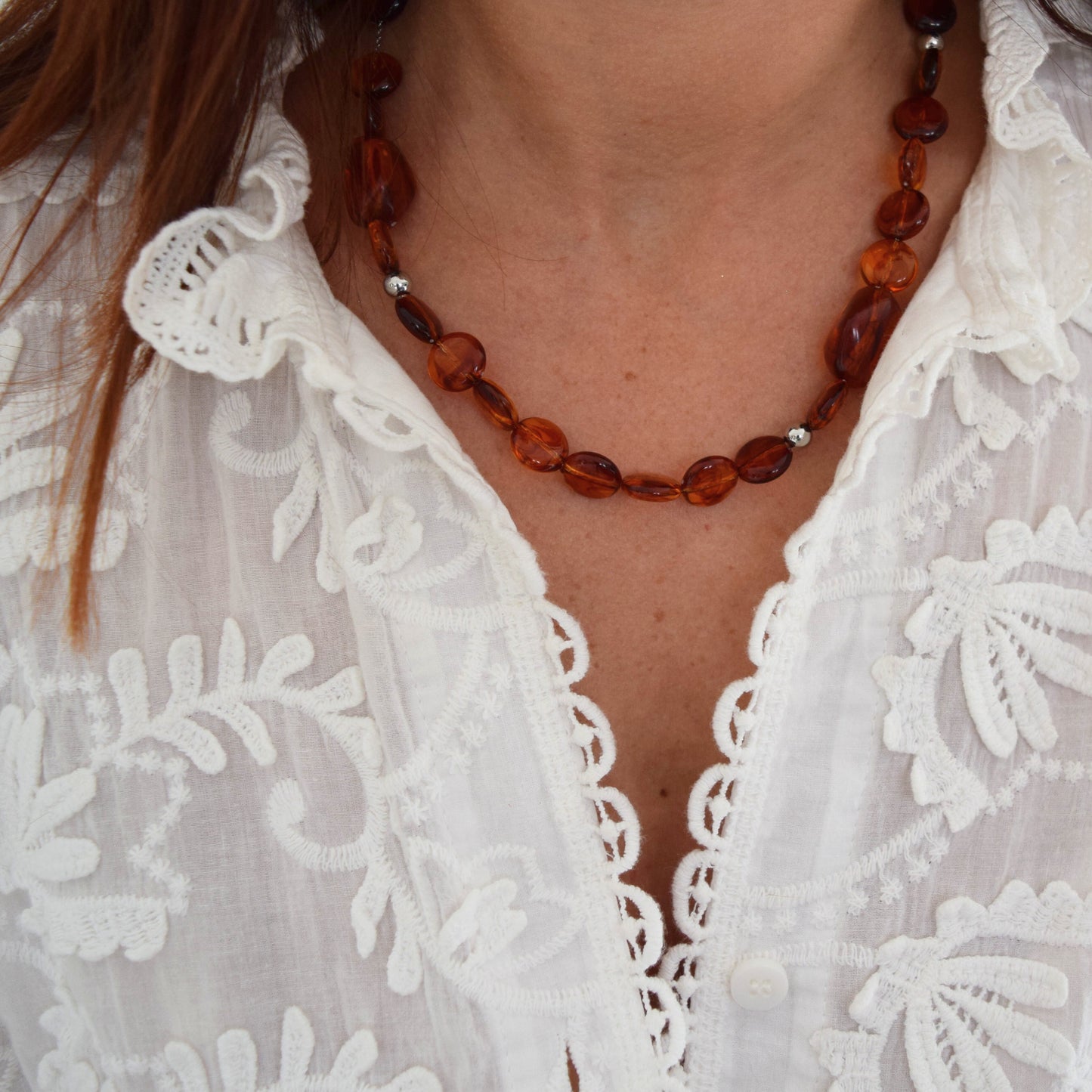 Gros plan sur collier ambre et acier inoxydable argenté, bijou fait main élégant.