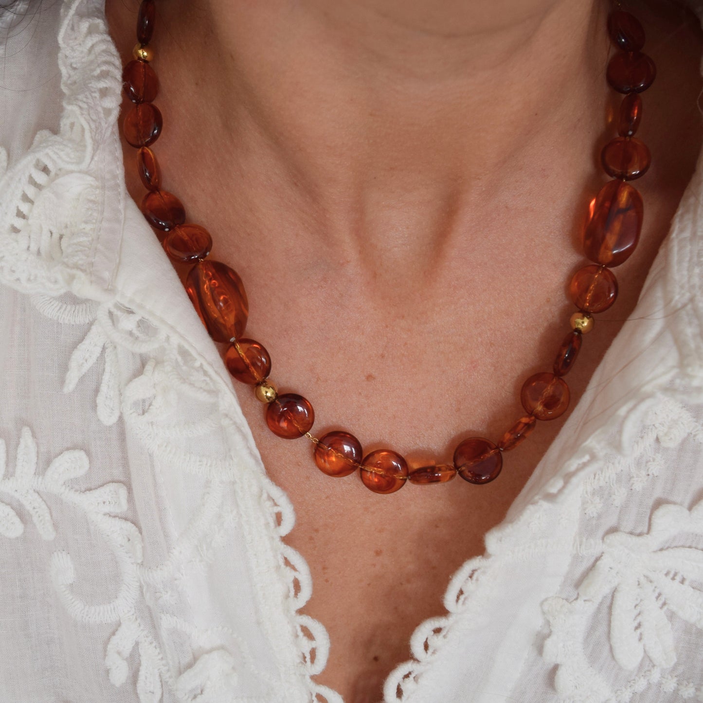 Gros plan sur collier ambre et acier inoxydable, bijou fait main élégant.