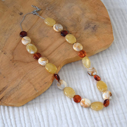 Vue rapprochée du collier artisanal sur fond naturel.