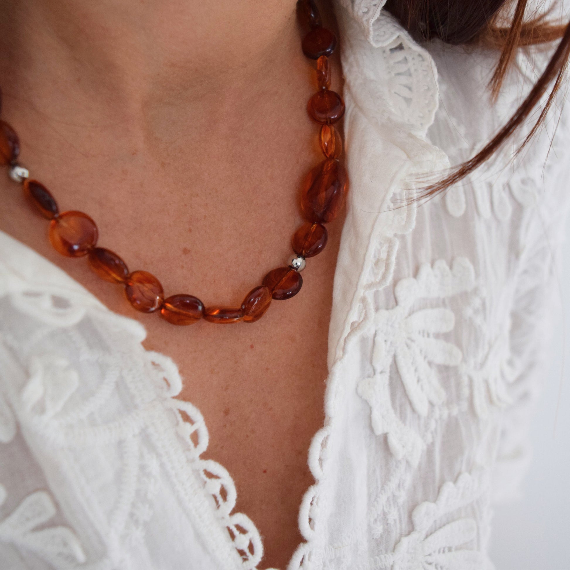 Détail des perles ovales en acrylique ambre avec intercalaires en acier inoxydable doré