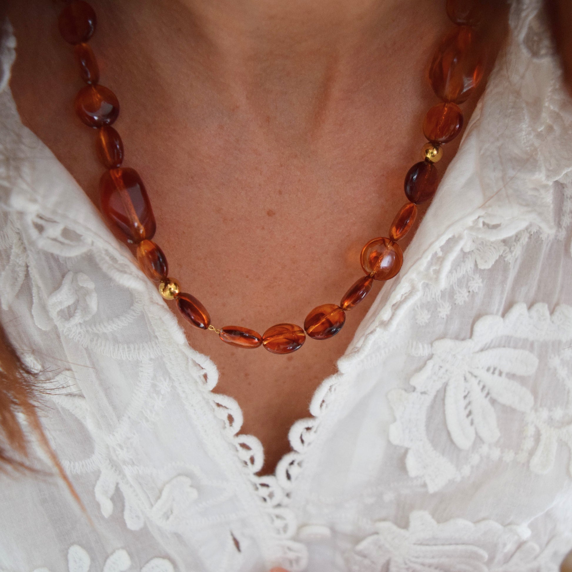 Vue rapprochée du collier ISOLDE porté, mettant en valeur la luminosité des perles ambre.