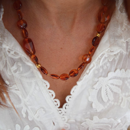 Vue rapprochée du collier ISOLDE porté, mettant en valeur la luminosité des perles ambre.