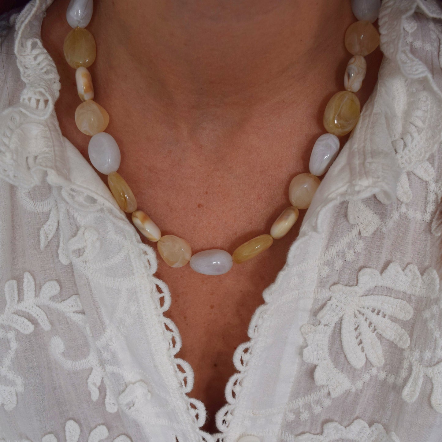 Zoom sur les perles ovales blanches et beige du collier artisanal