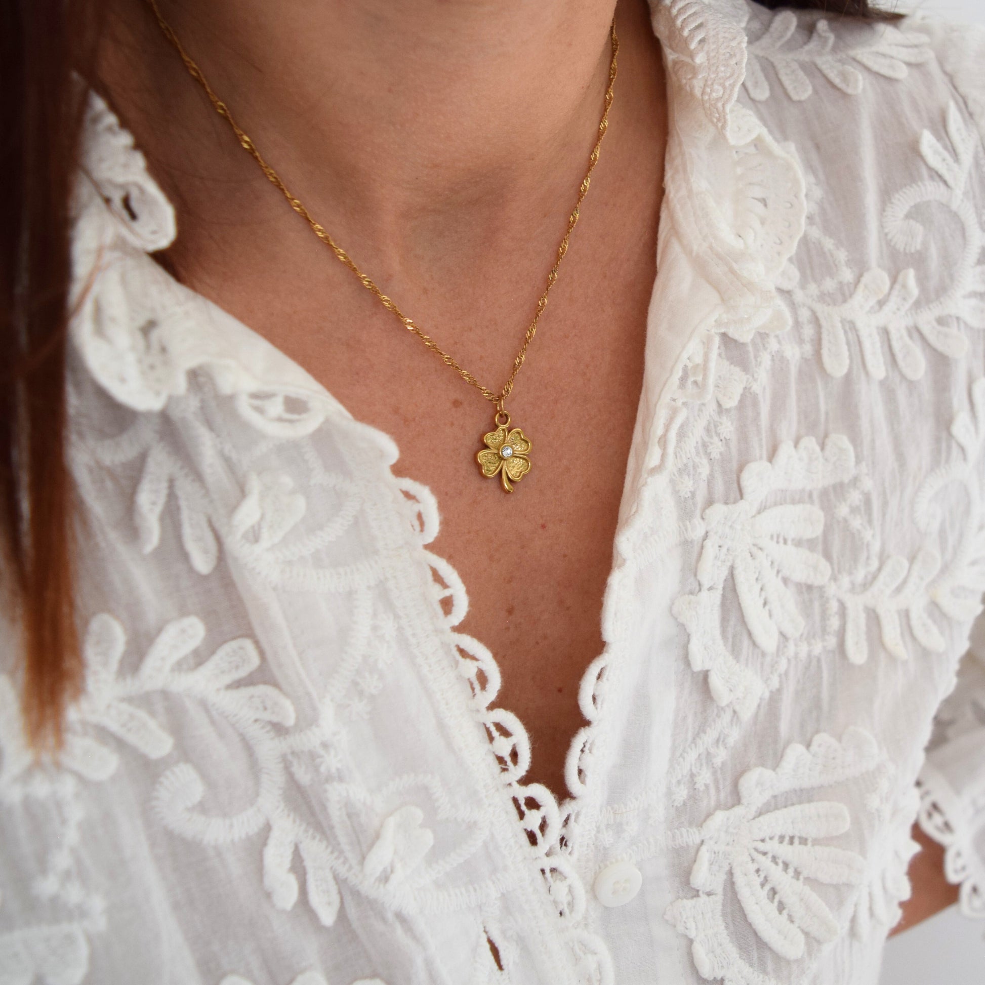 Détail du pendentif trèfle doré à l’or fin avec strass brillant